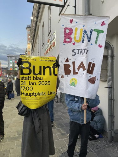 Zwei Personen halten Plakate hoch, auf denen "Bunt statt Blau" steht.