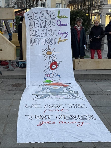 Ein langes weißes Transparent. Darauf steht: we are here, we are queer, we are angry without fear