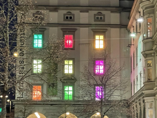 Die Fenster der Kunstuni Linz sind mit bunten Lichtern erleuchtet